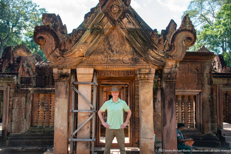 Visitor in a green shirt standing beneath an ornate sandstone gateway with temporary supports.
