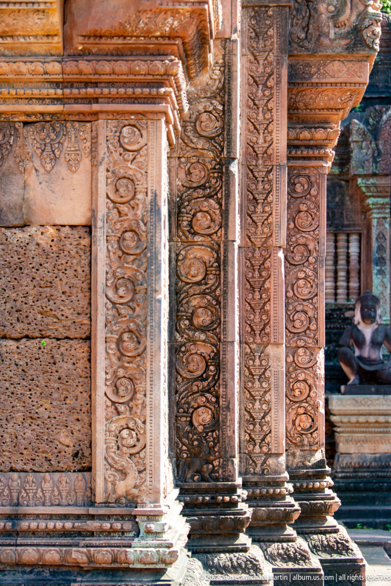 Close side view of carved sandstone pilasters, wall panels, and projecting temple moldings.