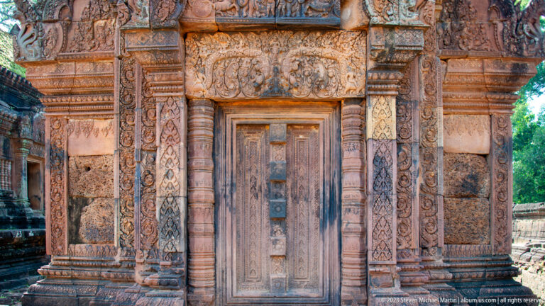 Closed central temple doorway framed by carved sandstone pilasters and floral bands.