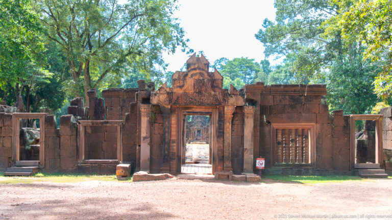 Frontal view of Banteay Srei's pink sandstone gateway with carved pediment and baluster windows.