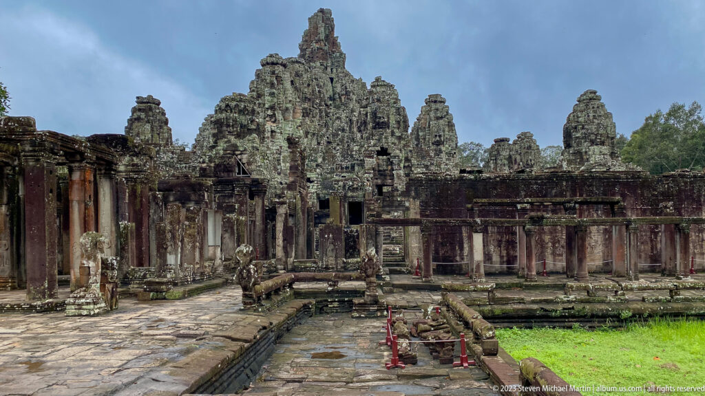 Wide view of Bayon Temple's central sanctuary, galleries, stone paths, and courtyard grass.