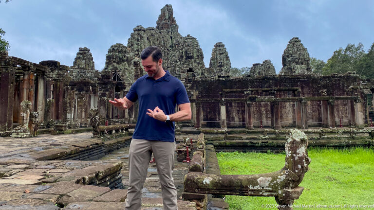 Male visitor standing beside a weathered naga balustrade at Bayon Temple.