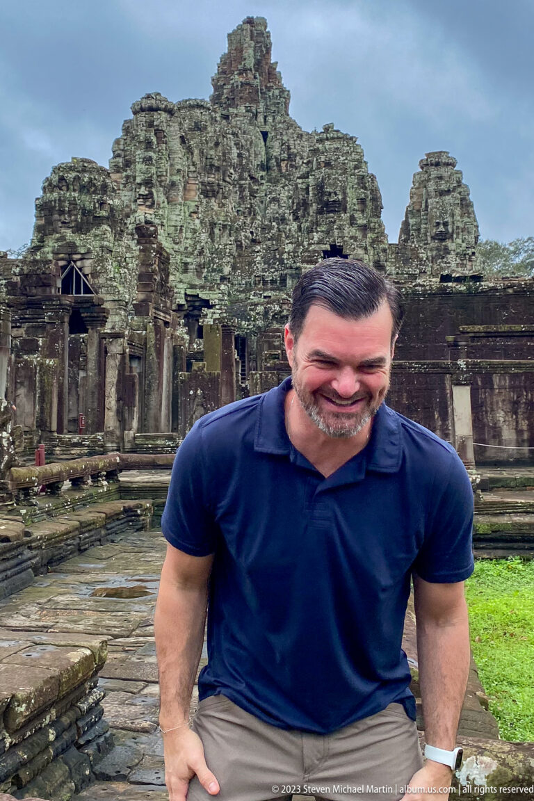 Male visitor leaning toward the camera in a playful distorted portrait at Bayon Temple.