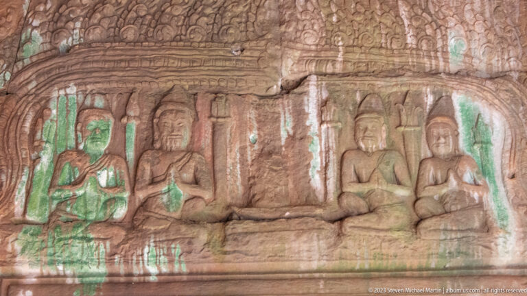 Faded seated figures beneath arches with red and green pigment streaks.