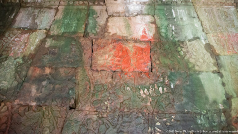 Weathered carved wall with broad green and red pigment patches.