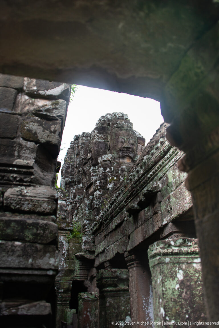 Ruined Bayon towers viewed through a dark stone passage.
