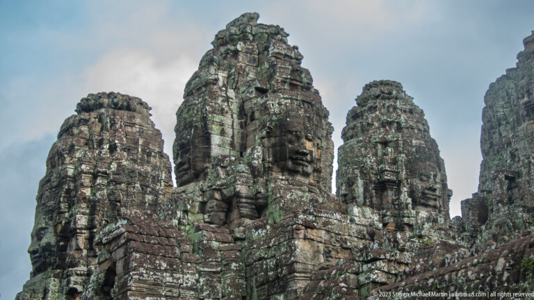 Several Bayon face towers rising above dense weathered stone galleries.