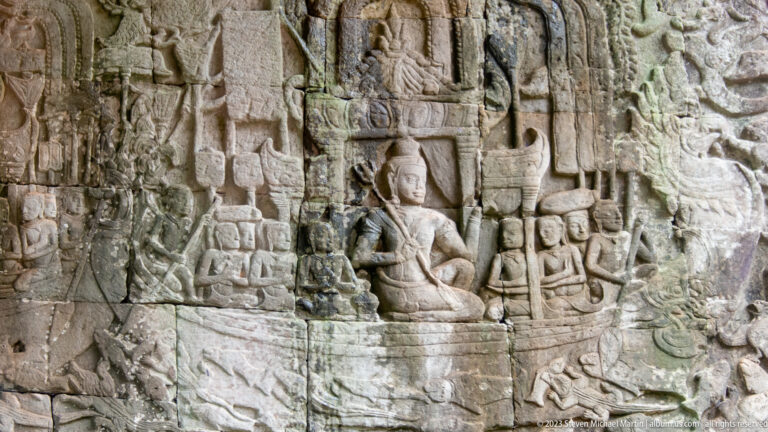 Khmer bas-relief with a large seated figure surrounded by smaller attendants.