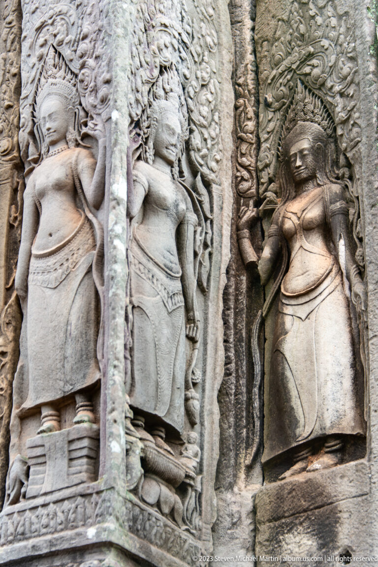 Three Khmer female deity reliefs standing in adjacent carved stone niches.