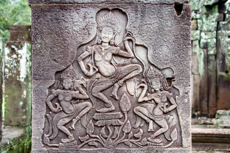 Carved panel with a dancing female figure above smaller attendants and animals.