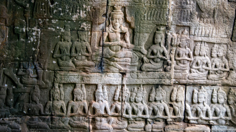 Multi-register Khmer relief with seated principal figures and rows of attendants.
