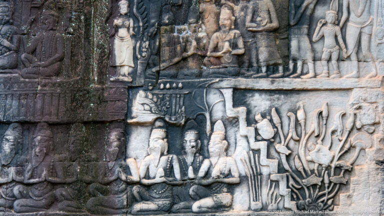 Two-register Khmer relief with seated figures above and animated performers below.