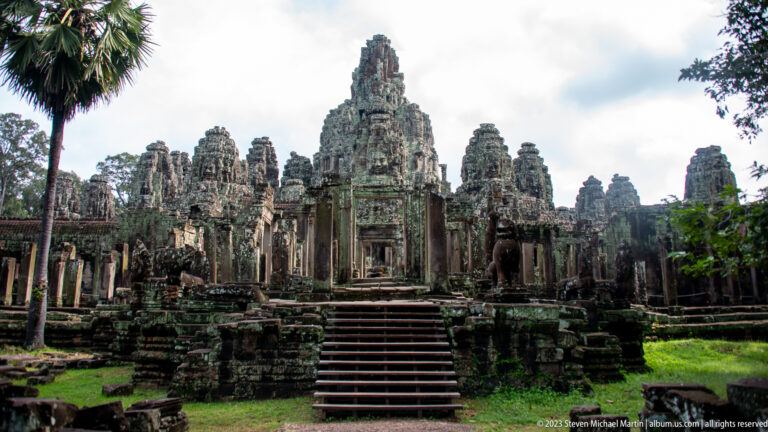 Frontal view up stone steps toward Bayon Temple's central entrance, galleries, and clustered face towers.