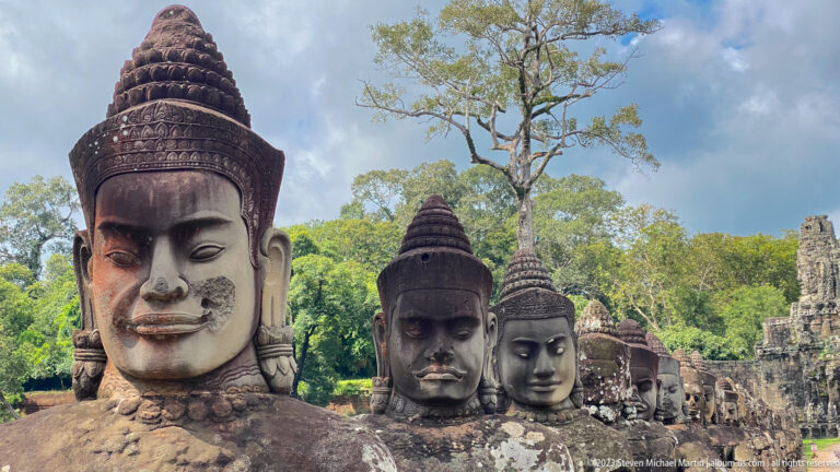 Close view of several crowned stone heads from the monumental causeway figures at Angkor Thom.