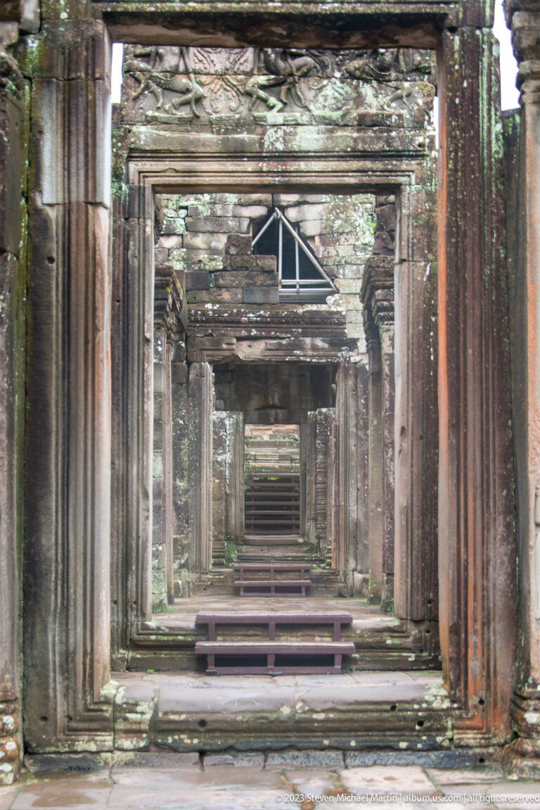 Long interior corridor at Bayon Temple formed by repeated sandstone doorways and columns.