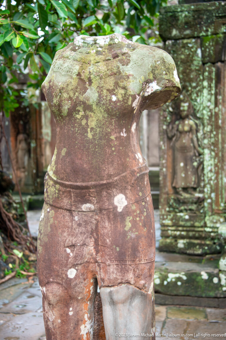 Headless weathered sandstone female torso with a narrow waist and rounded hips at Bayon Temple.