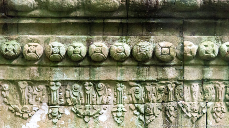 Weathered sandstone bands with repeating lotus-bud shapes above a carved foliate frieze.