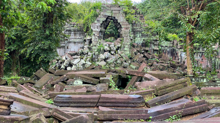 Pointed temple opening rises above a dense field of fallen sandstone blocks at Beng Mealea.