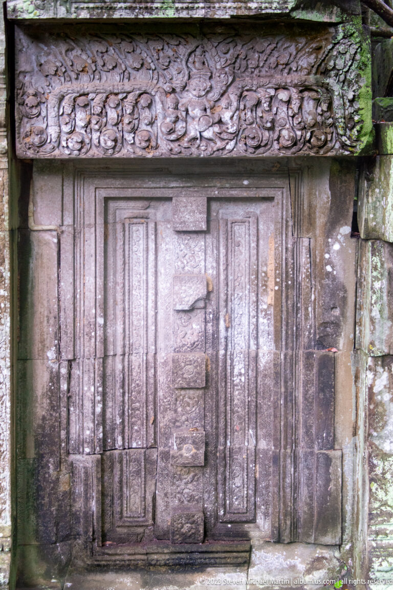 Closed sandstone false door with stepped panels beneath a richly carved foliate lintel.