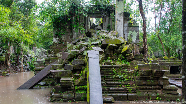 Timber ramp leading to a raised ruined sandstone structure with collapsed steps and entrance.