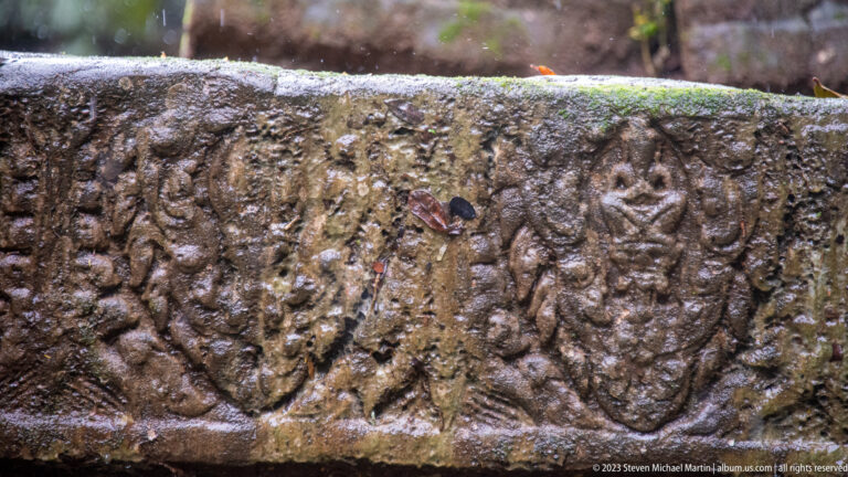Weathered sandstone frieze carved with repeated leaf-shaped medallions and curling foliage along its surface.
