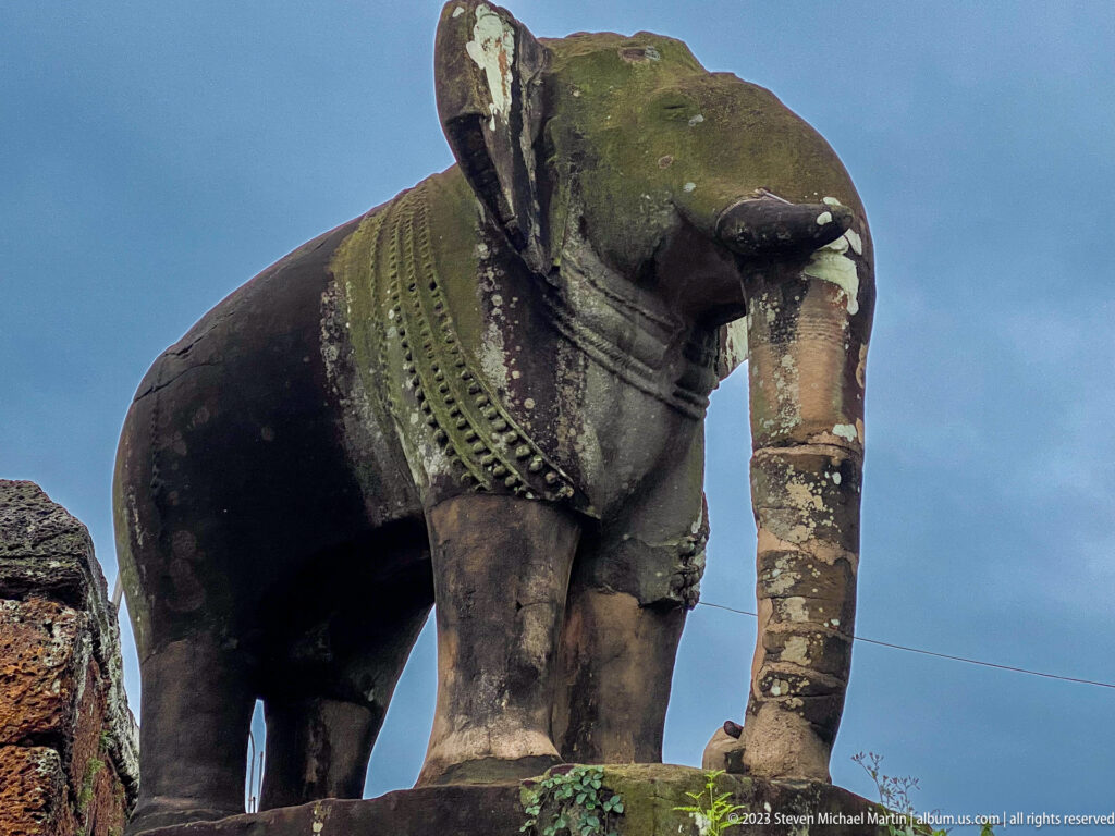 Low-angle three-quarter view of the weathered stone guardian elephant at East Mebon.