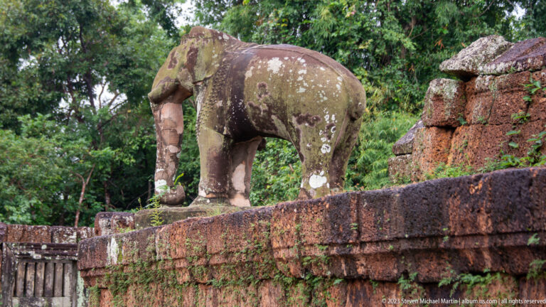 Profile of weathered stone elephant standing on temple wall.