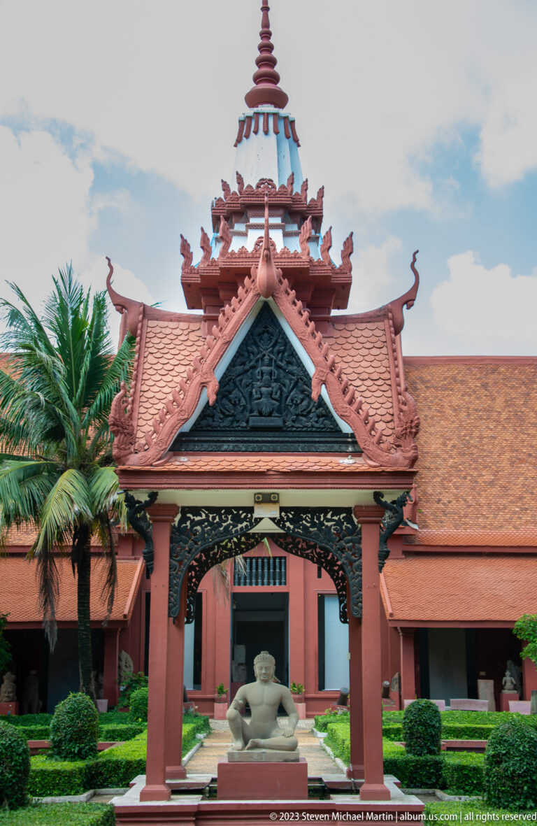 Khmer-style entrance pavilion framing a seated stone sculpture in the museum courtyard.