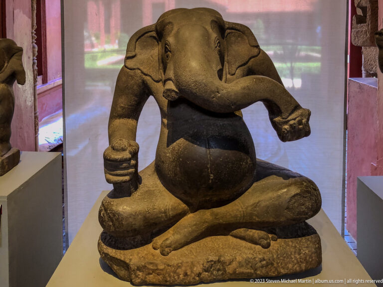 Seated stone Ganesha with crossed legs, rounded body, and prominent elephant trunk.