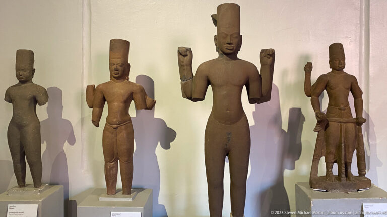 Group of standing Khmer stone figures displayed in the National Museum of Cambodia gallery.