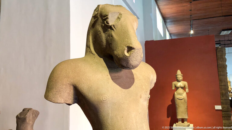 Horse-headed anthropomorphic sandstone figure displayed in the National Museum of Cambodia gallery.
