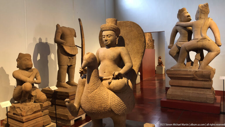 Seated deity riding a bird mount displayed in the National Museum of Cambodia gallery.