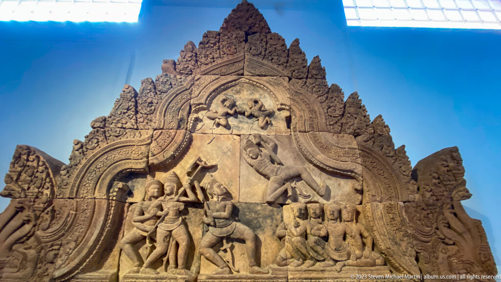 Narrative temple pediment relief displayed in the National Museum of Cambodia gallery.