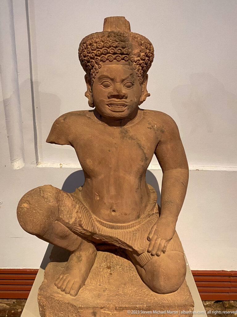 Alternate view of kneeling guardian displayed in the National Museum of Cambodia gallery.