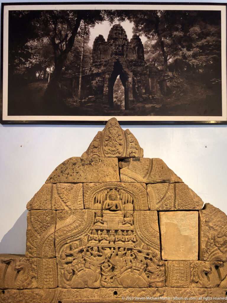 Reconstructed triangular Khmer pediment assembled from carved architectural fragments with visible gaps.