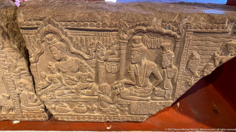 Fragmentary sandstone relief with several seated figures, architectural motifs, and decorative borders.