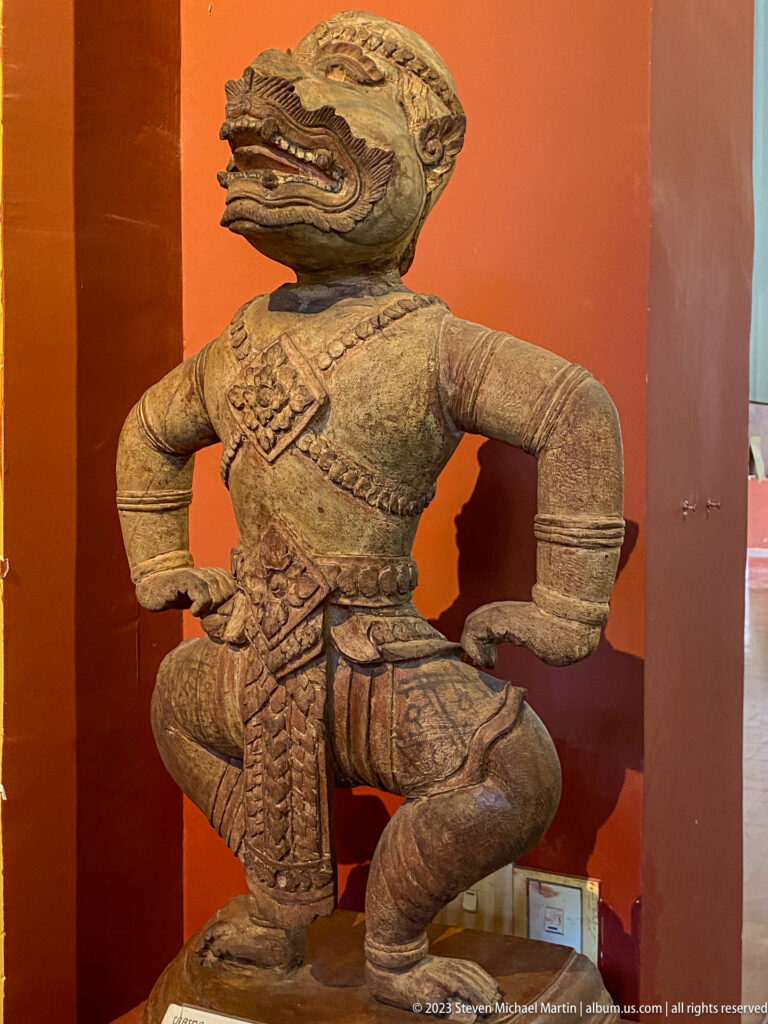 Kneeling hybrid guardian with a crocodile-like head, bent legs, and hands at the waist.