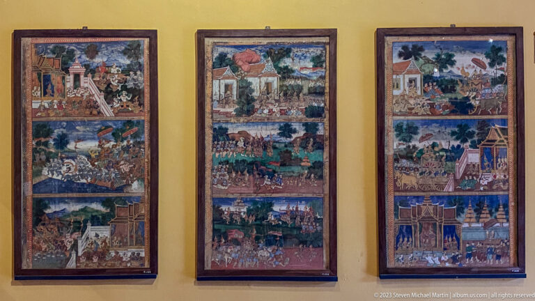 Three tall narrative paintings filled with architecture, landscapes, processions, and ceremonial figures.