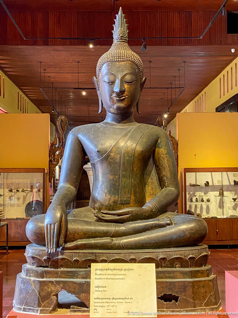 Large seated bronze Buddha touching the earth with one hand and resting the other in his lap.