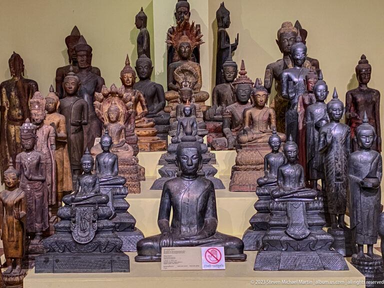 Dense group of seated and standing Buddha images arranged around a monumental central figure.