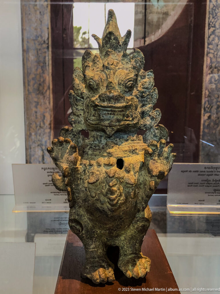 Weathered bronze ritual vessel with a fierce guardian face and projecting ornamental forms.