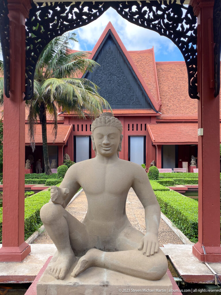 Seated sandstone figure in courtyard at the National Museum of Cambodia.
