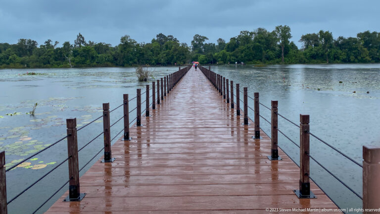 Long wet boardwalk extending across flooded water.