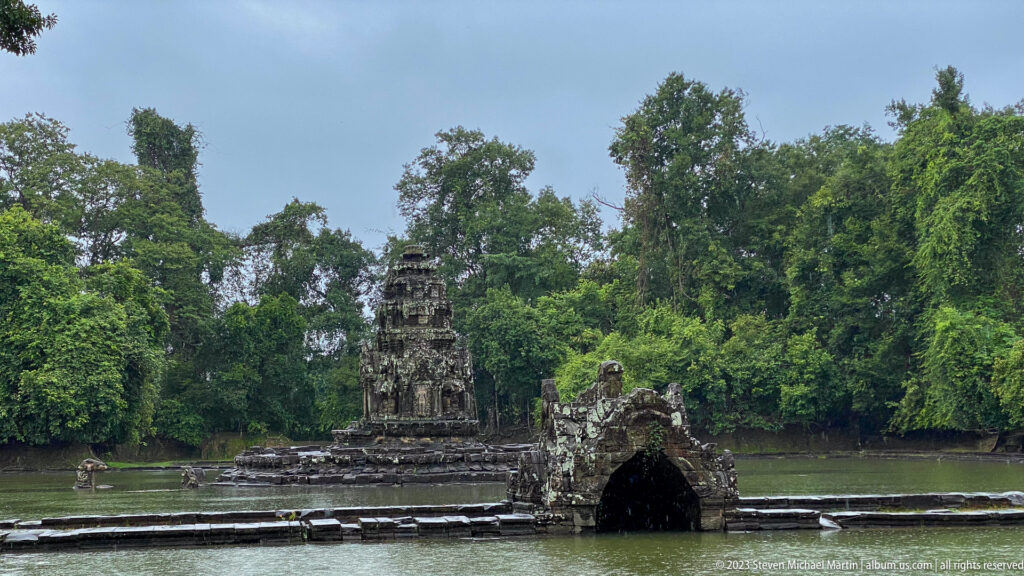 Central sanctuary of Neak Poan beyond the carved naga bridge across the surrounding reservoir.