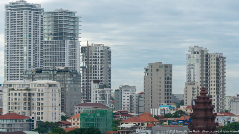 Cluster of pale apartment towers beyond low red-roofed buildings in Phnom Penh.