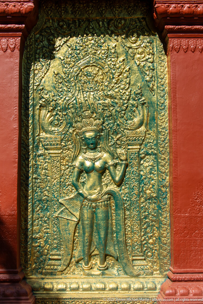 Frontal crowned figure in gilded relief standing between columns within dense ornamental decoration.