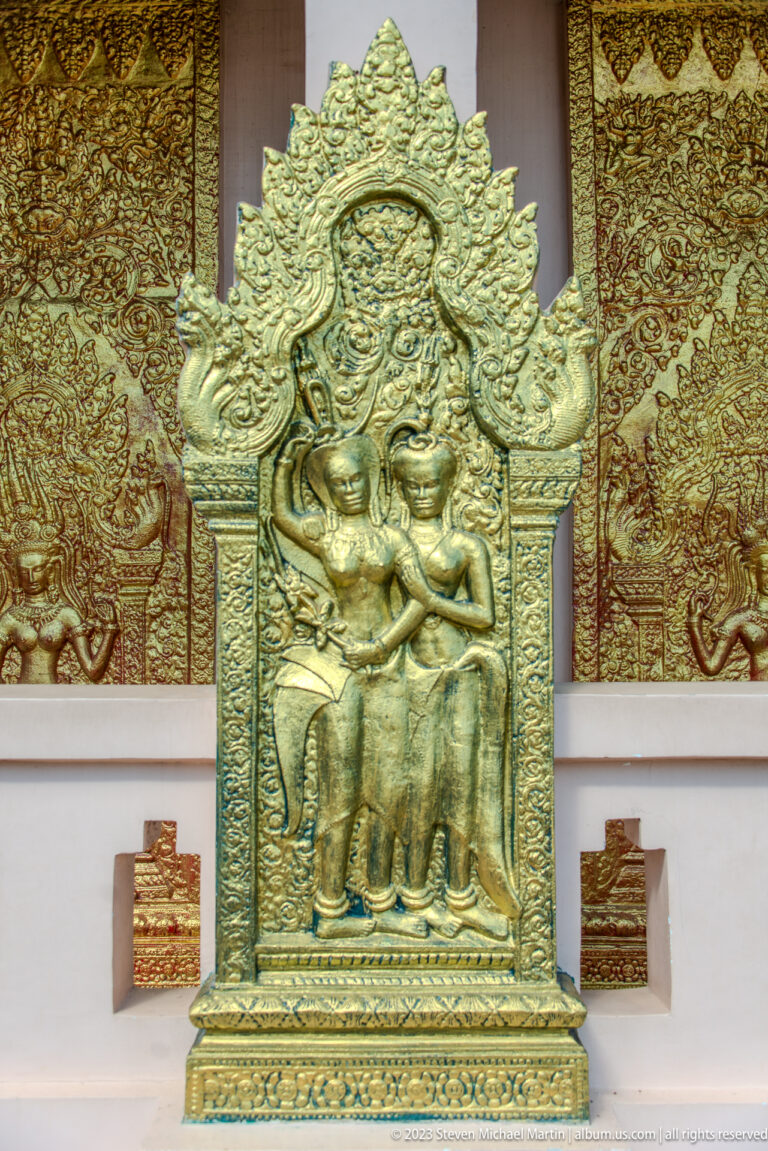 Gilded relief of several seated figures within an ornate flame-shaped frame.