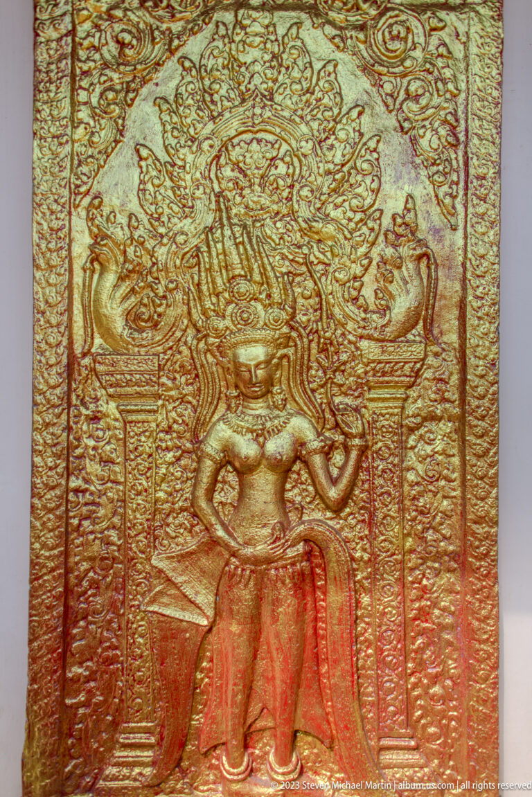 Close gilded panel with a crowned standing figure between pillars and smaller surrounding forms.