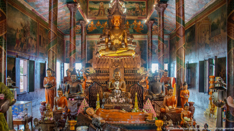 Tiered Buddhist altar crowded with Buddha statues, lotus offerings, vessels, and carved platforms.