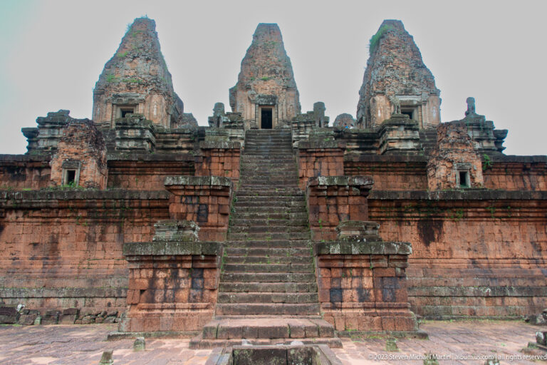 Wide frontal elevation of Pre Rup with a central stair, broad brick terraces, and three towers above.